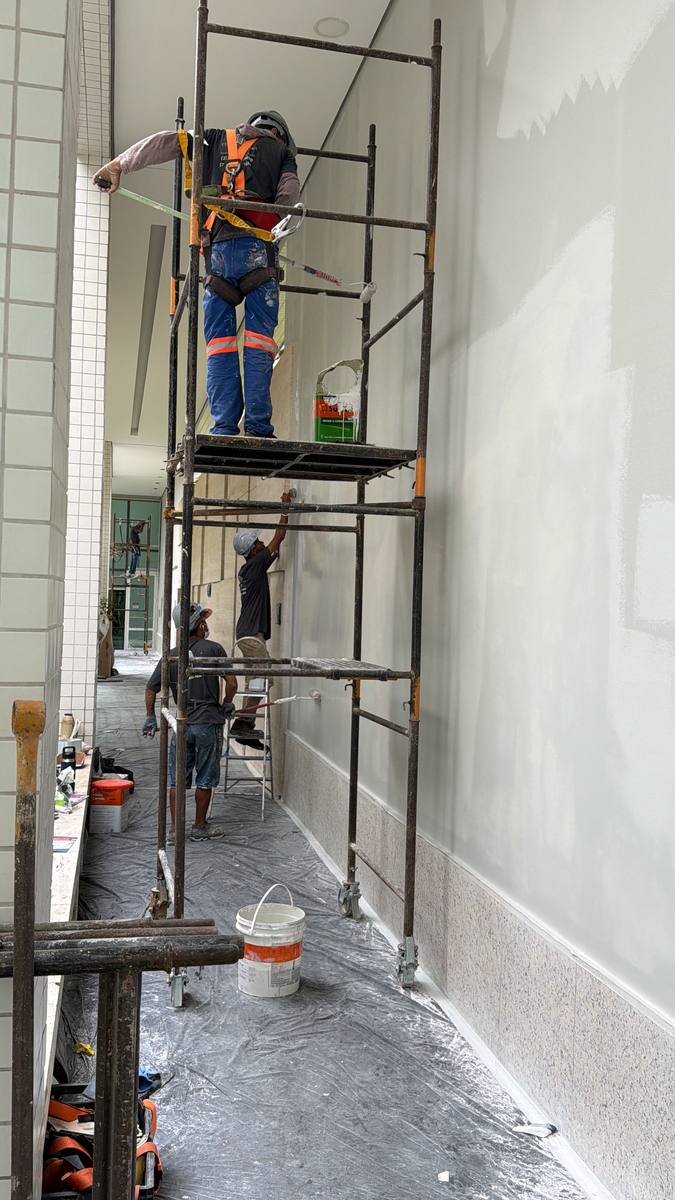 Pintura de teto de pilotis sobre andaime, em área comum de condomínio